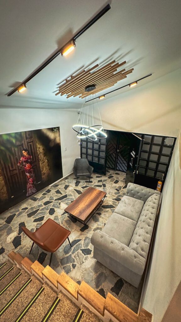Salón de la tienda con lámpara circular, sofá gris y piso de mosaico