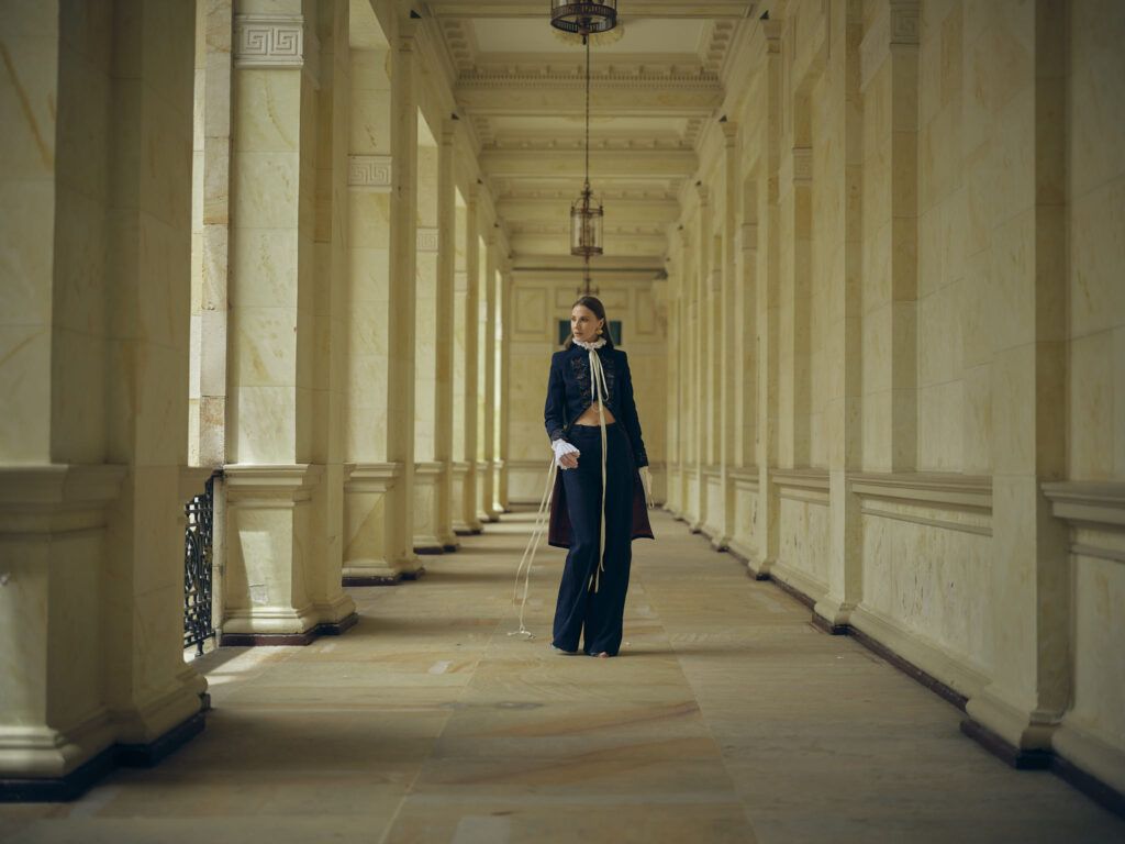 Look de sastrería oscura en un corredor de columnas, colección Guadalupe de Diego Guarnizo