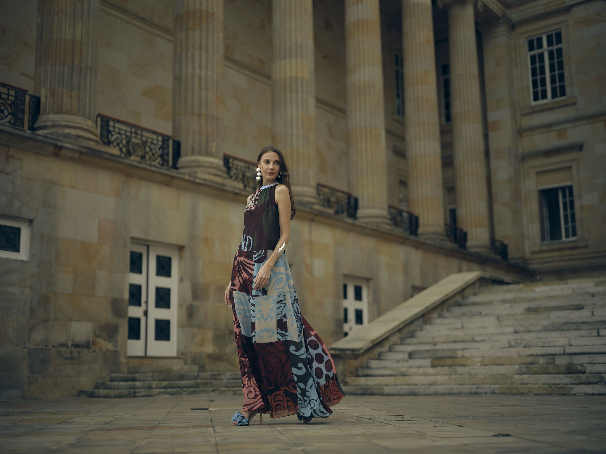 Modelo con vestido largo estampado de la colección Guadalupe frente a las escalinatas de un edificio republicano